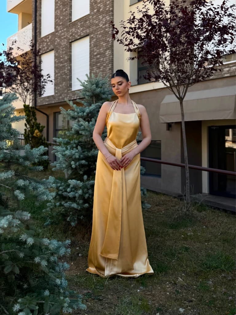 Gold sash satin dress — front view, hands clasped